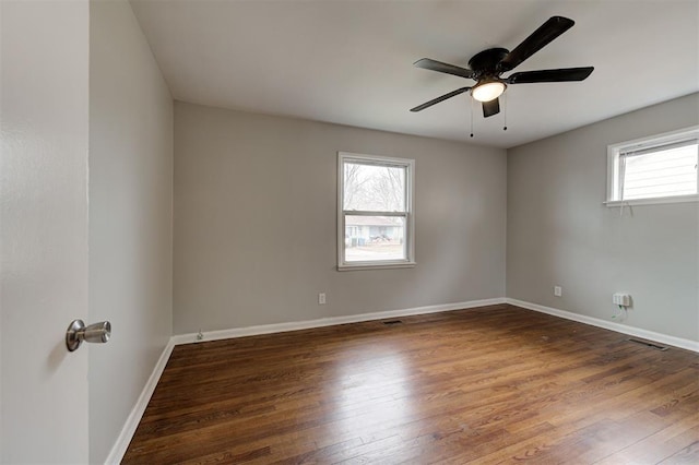 spare room with ceiling fan, visible vents, baseboards, and wood finished floors