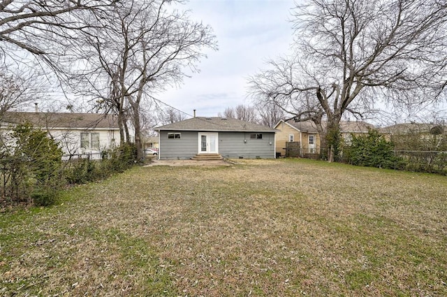 back of property featuring entry steps, a yard, and fence