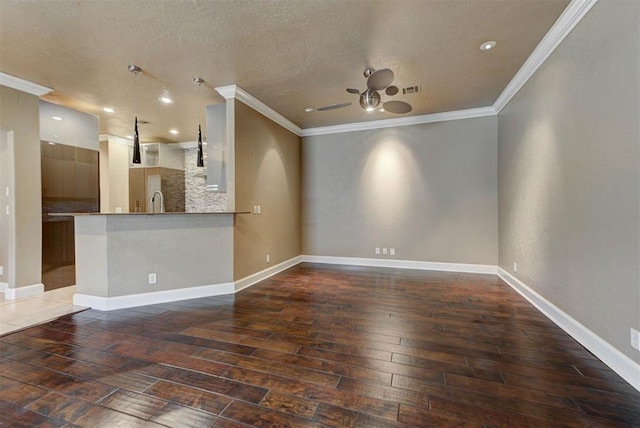 unfurnished living room featuring a ceiling fan, baseboards, visible vents, wood-type flooring, and crown molding