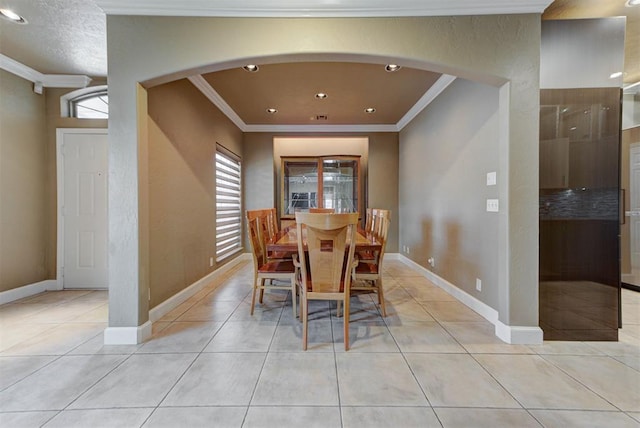 dining space featuring light tile patterned floors, baseboards, arched walkways, and crown molding