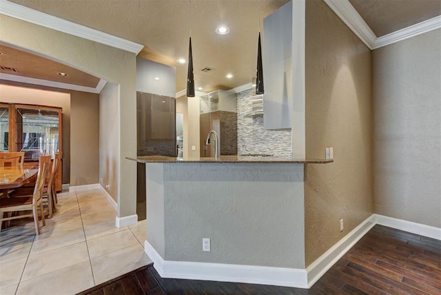 kitchen featuring tasteful backsplash, light wood finished floors, crown molding, dark stone counters, and a sink