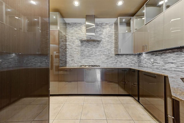 kitchen with modern cabinets, wall chimney exhaust hood, light tile patterned floors, light stone countertops, and stainless steel gas cooktop