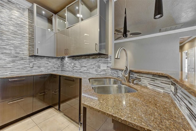 kitchen with crown molding, tasteful backsplash, stone counters, and a sink