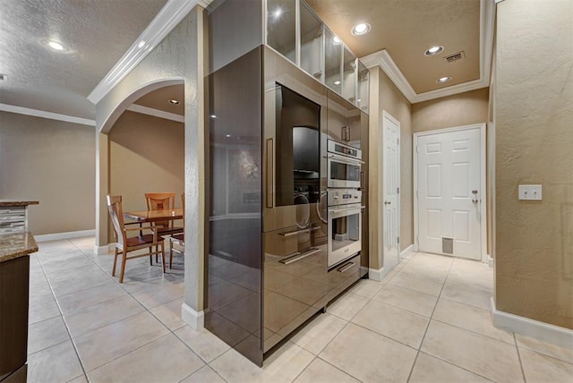 kitchen with light tile patterned floors, visible vents, arched walkways, a textured ceiling, and modern cabinets