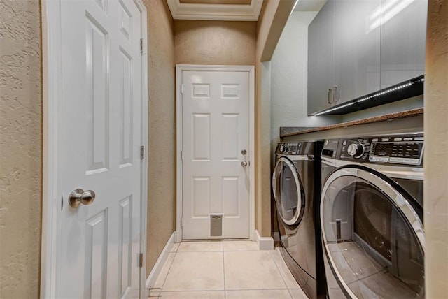 laundry room featuring light tile patterned floors, independent washer and dryer, cabinet space, and a textured wall