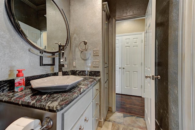 bathroom with decorative backsplash, vanity, and a textured wall