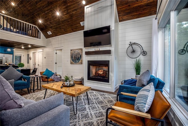 living area with wooden walls, wood ceiling, a fireplace, wood finished floors, and high vaulted ceiling