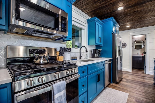 kitchen with blue cabinetry, a sink, light countertops, appliances with stainless steel finishes, and wooden ceiling