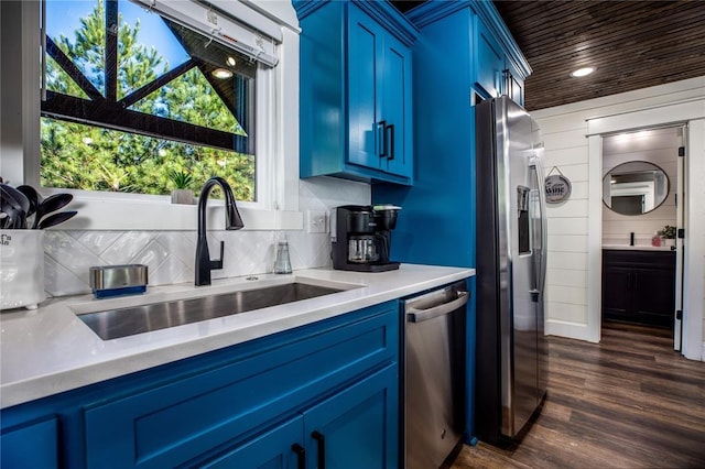 kitchen with tasteful backsplash, a sink, blue cabinetry, stainless steel appliances, and dark wood-style flooring