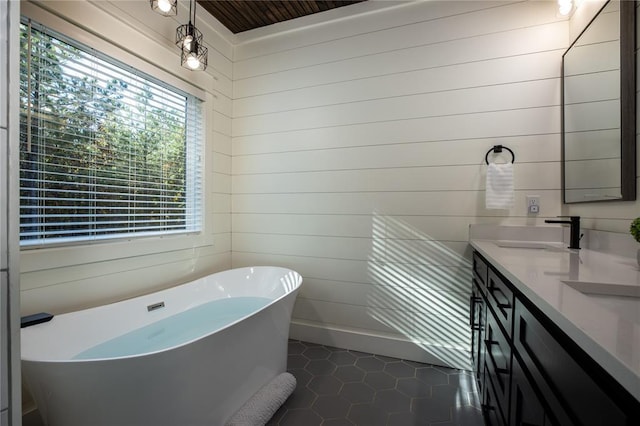 full bath featuring a sink, wooden walls, tile patterned flooring, double vanity, and a soaking tub