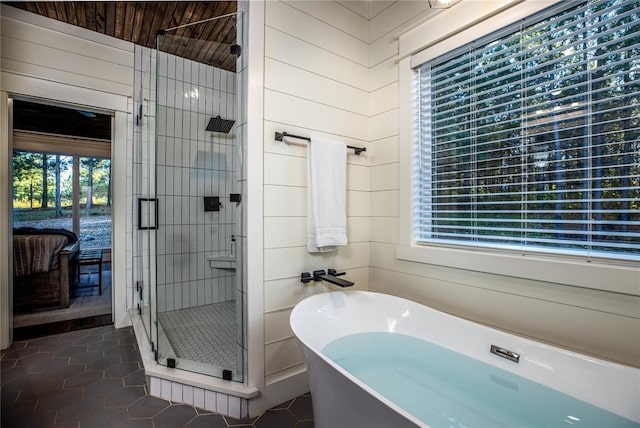 full bathroom featuring tile patterned flooring, a soaking tub, a stall shower, and ensuite bath