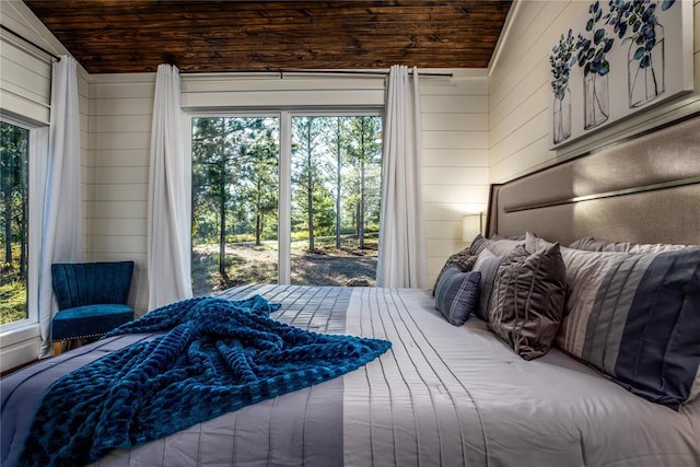 bedroom with multiple windows, wood ceiling, and wood walls