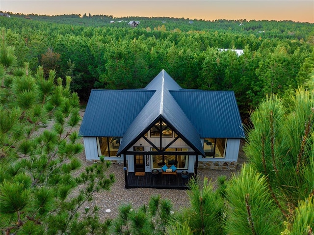 back of house at dusk with a forest view and metal roof