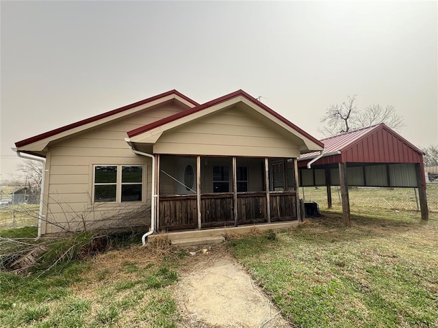 view of front facade with fence, a detached carport, a front lawn, and a sunroom