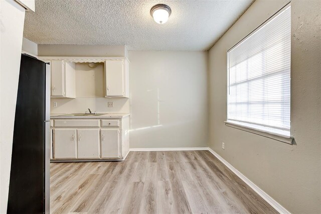 3333 S Walker Ave, Oklahoma City, OK 73109 - unfurnished dining area with a sink, baseboards, light wood-style floors, and a textured ceiling