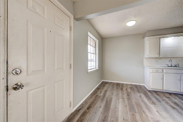 3333 S Walker Ave, Oklahoma City, OK 73109 - unfurnished dining area featuring a textured ceiling, light wood-type flooring, baseboards, and a sink