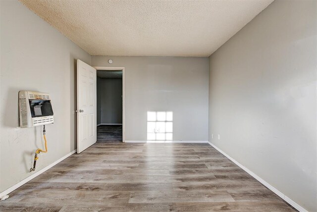 3333 S Walker Ave, Oklahoma City, OK 73109 - unfurnished room with heating unit, wood finished floors, baseboards, and a textured ceiling
