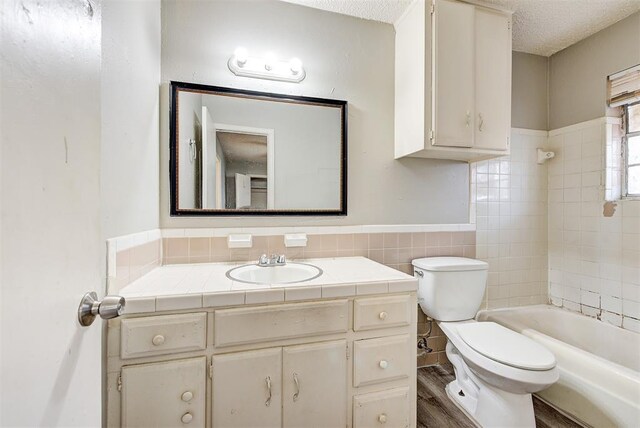 3333 S Walker Ave, Oklahoma City, OK 73109 - bathroom with toilet, a textured ceiling, wood finished floors, tile walls, and vanity