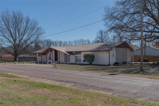 ranch-style home with a front lawn and fence