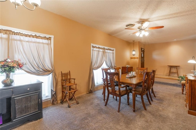 carpeted dining area with baseboards, a textured ceiling, and ceiling fan