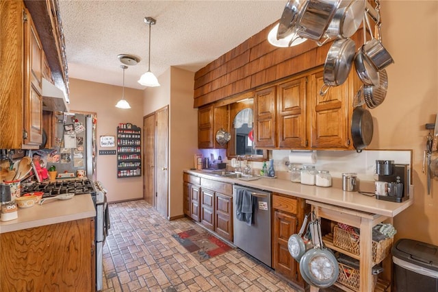 kitchen featuring brick floor, stainless steel appliances, light countertops, a textured ceiling, and brown cabinets