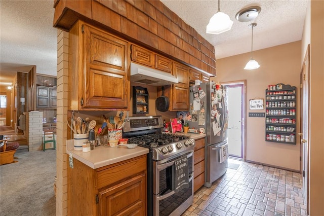 kitchen with brown cabinets, under cabinet range hood, a textured ceiling, stainless steel appliances, and light countertops