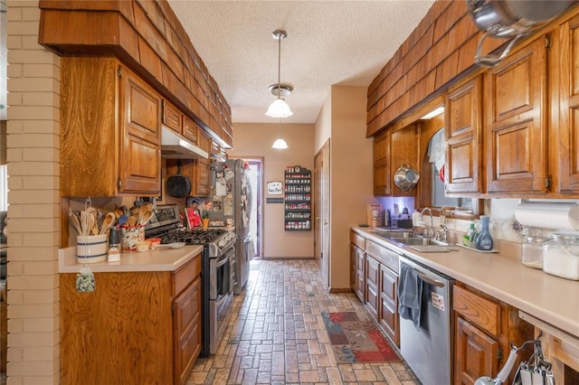 kitchen featuring under cabinet range hood, light countertops, brown cabinetry, stainless steel appliances, and a sink