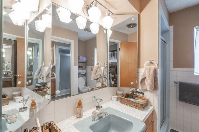 full bathroom featuring vanity, tile walls, a stall shower, and wainscoting