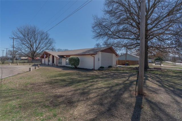 view of side of home with a lawn and fence