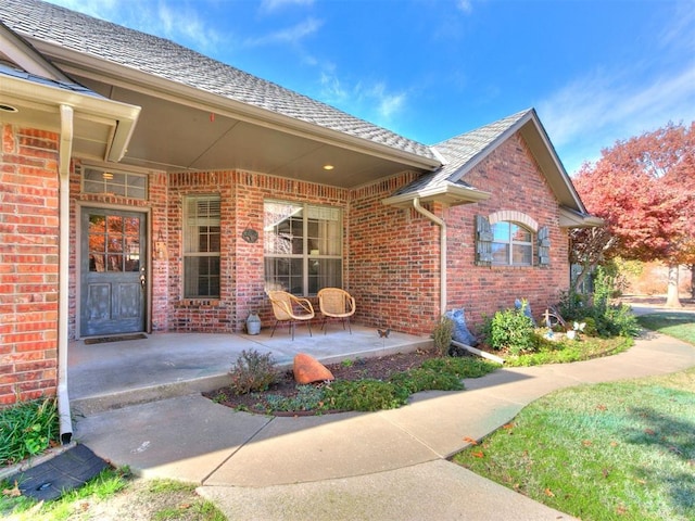 doorway to property featuring brick siding and covered porch