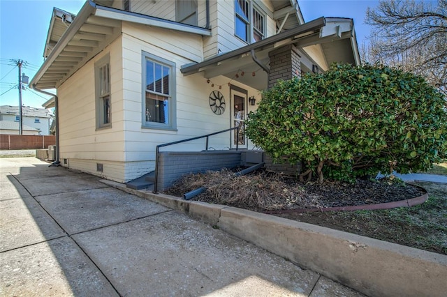 view of side of home with concrete driveway, fence, and crawl space