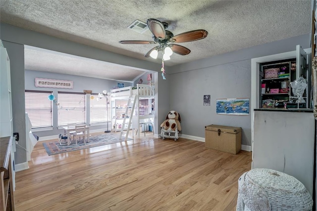 rec room with visible vents, baseboards, ceiling fan, wood finished floors, and a textured ceiling