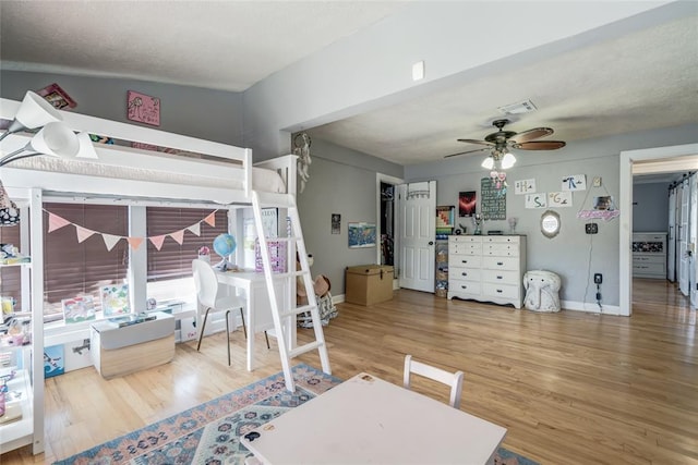 bedroom featuring visible vents, a ceiling fan, baseboards, and wood finished floors