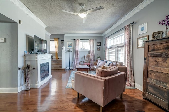 living area with baseboards, wood finished floors, a ceiling fan, and crown molding