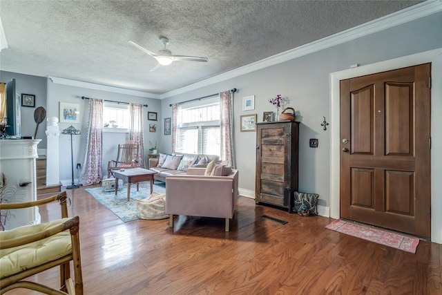 living room featuring ceiling fan, a textured ceiling, wood finished floors, and ornamental molding