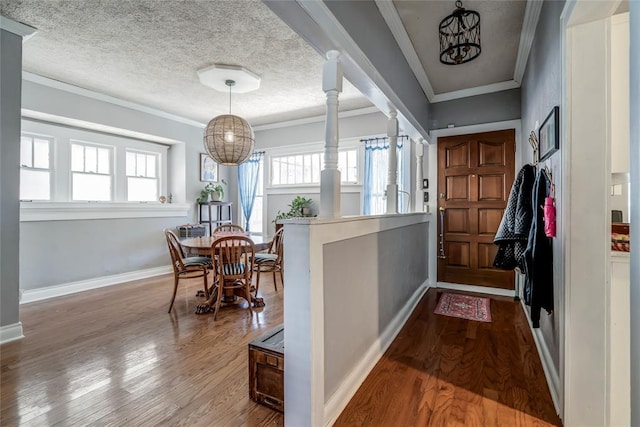 foyer with a textured ceiling, wood finished floors, an inviting chandelier, crown molding, and baseboards