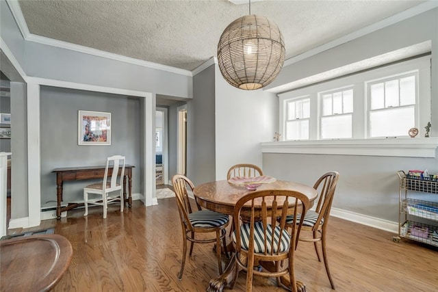 dining space featuring crown molding, wood finished floors, baseboards, and a textured ceiling