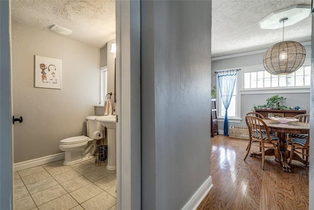 interior space with a textured ceiling, light wood-type flooring, and baseboards