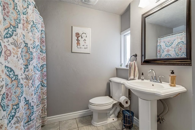 full bathroom with toilet, curtained shower, a textured ceiling, tile patterned flooring, and baseboards