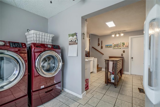 clothes washing area with light tile patterned floors, baseboards, separate washer and dryer, and a textured ceiling