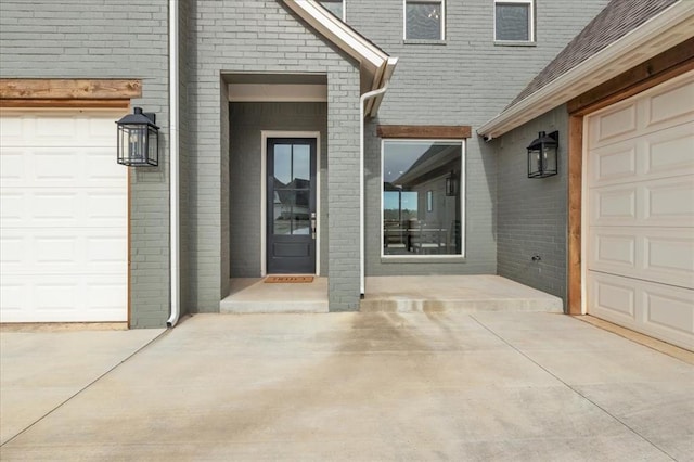 property entrance featuring a garage, brick siding, and concrete driveway