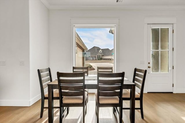 dining room with crown molding, baseboards, and wood finished floors