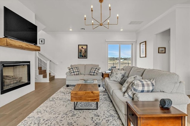 living area with visible vents, ornamental molding, wood finished floors, a chandelier, and stairs