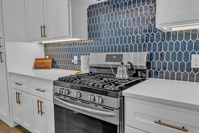 kitchen featuring backsplash, wood finished floors, white cabinetry, gas stove, and light stone countertops