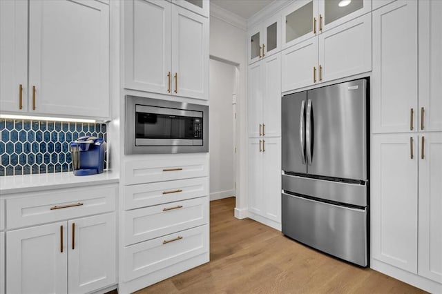 kitchen with backsplash, crown molding, light countertops, appliances with stainless steel finishes, and white cabinetry