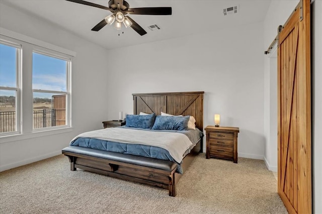 bedroom featuring baseboards, a barn door, light carpet, and visible vents