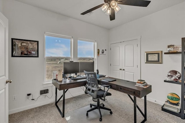 carpeted home office featuring baseboards and ceiling fan