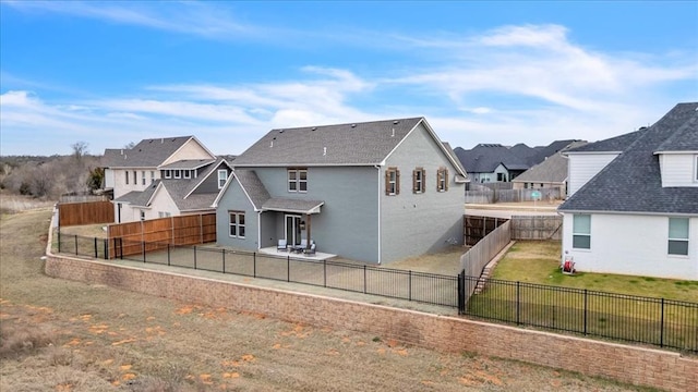 rear view of property featuring a residential view, a lawn, a patio, and a fenced backyard