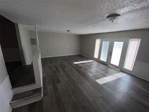 unfurnished living room featuring a textured ceiling and wood finished floors