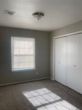 unfurnished bedroom with baseboards, visible vents, and a closet